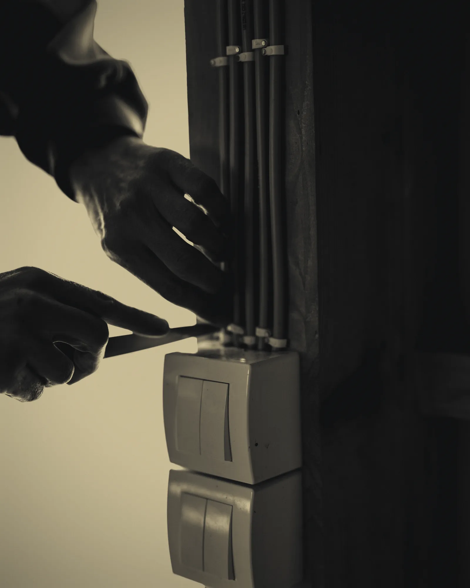 Électricien raccordant un interrupteur à côté d'un faisceau de gaines